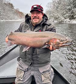 fisherman in Salmon River holding a steelhead in the winter